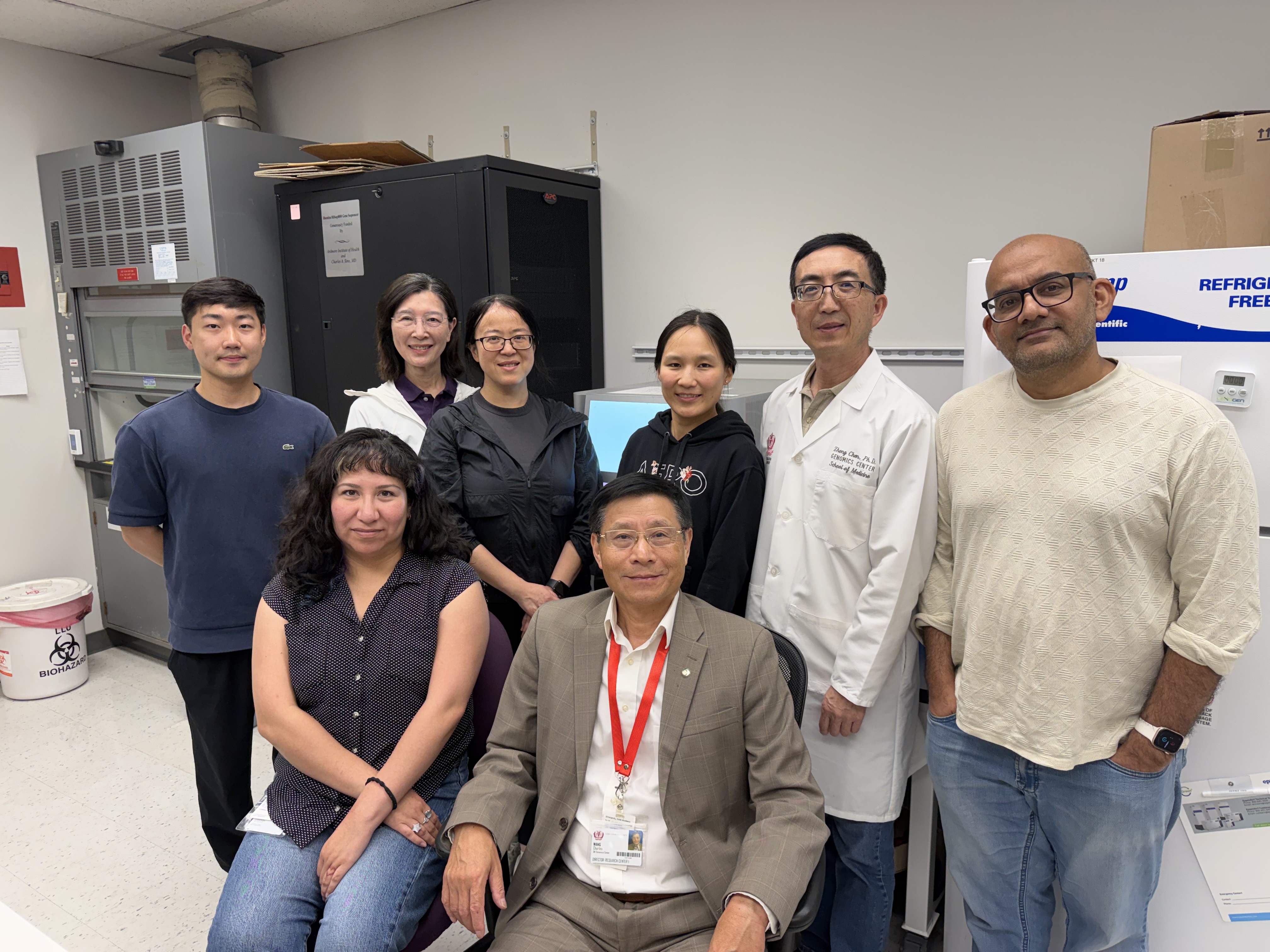 Eight people standing in a group in a science lab looking at camera