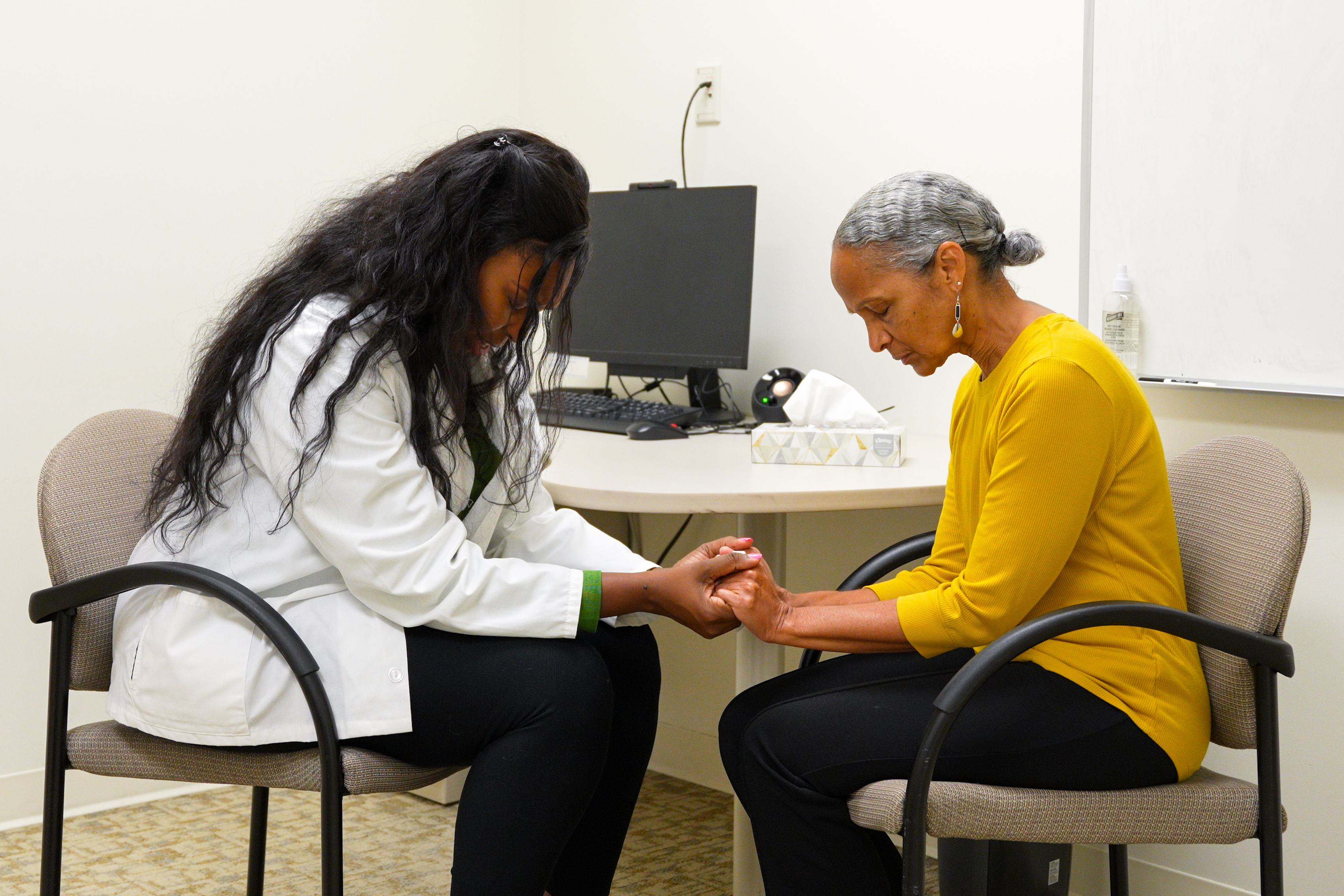 Student praying with patient