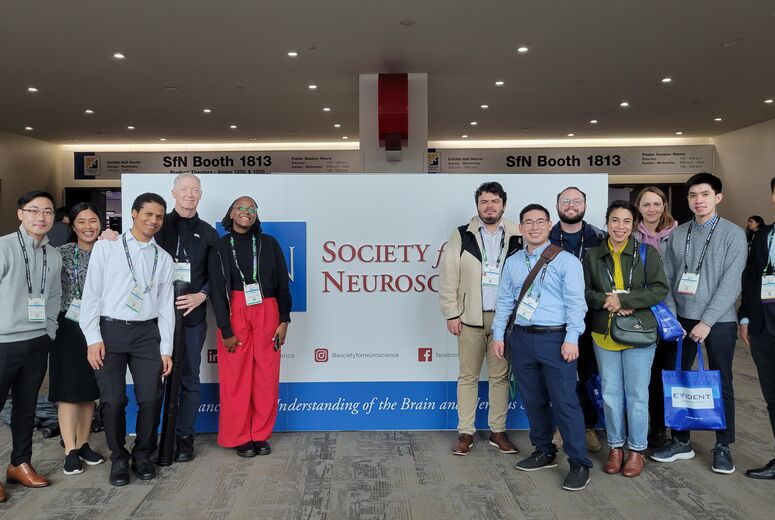 Group of faculty and students in front of a backdrop at a conference 
