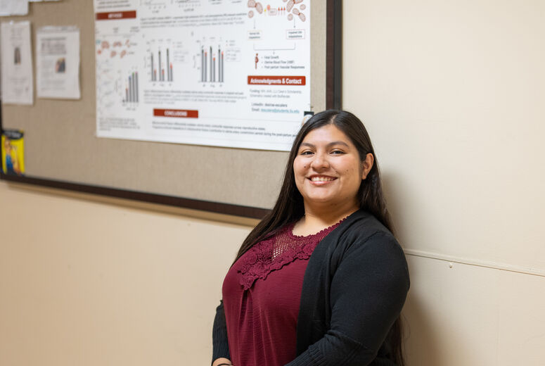 female student standing in front of a research poster