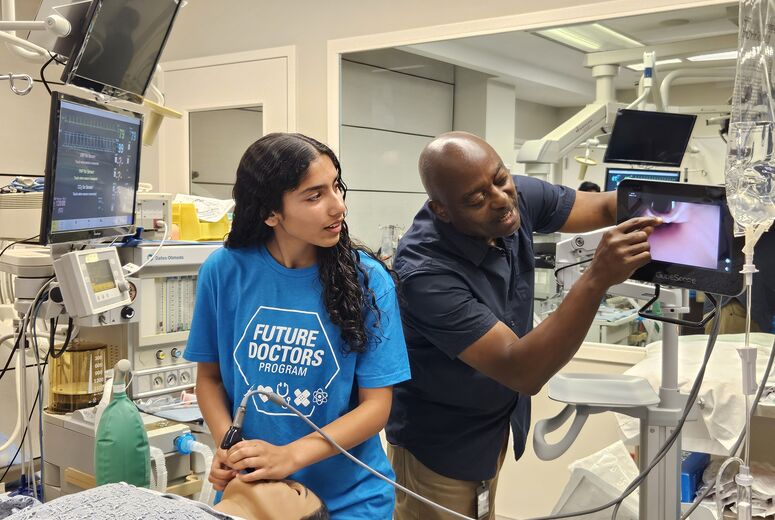 Student using device in a manikin with professor