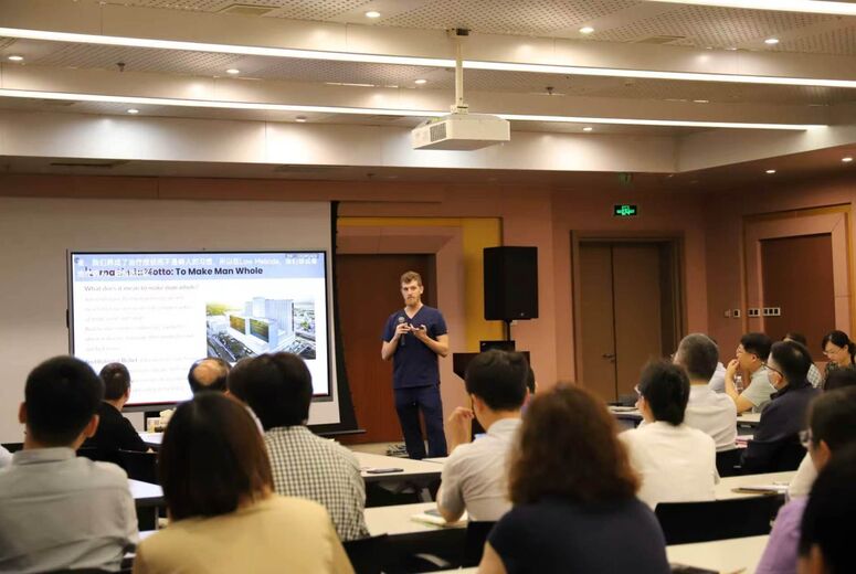 Medical student presenting research on a screen to a group of individuals at tables
