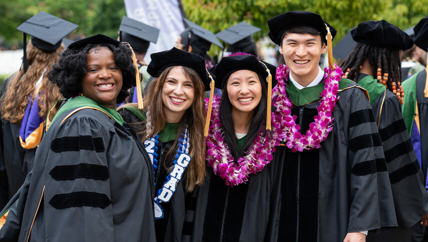 graduates in black regalia smiling